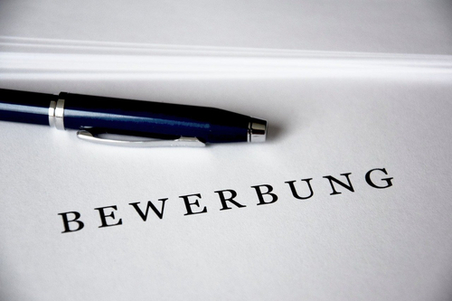 Blauer Kugelschreiber auf einem Dokument mit der Aufschrift „BEWERBUNG“